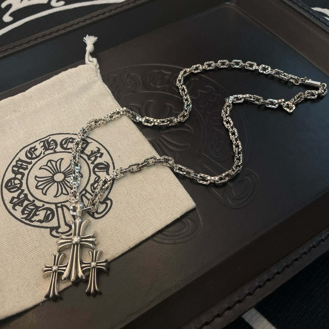 Silver cross pendant necklace on fabric pouch with chain links visible