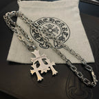 Silver cross pendant necklace with layered chain on fabric pouch