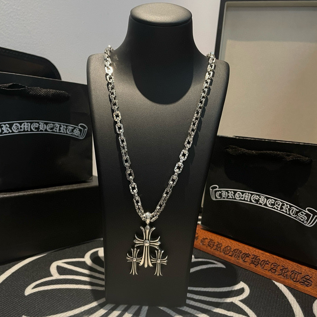 Silver chain necklace with cross pendant on black display bust