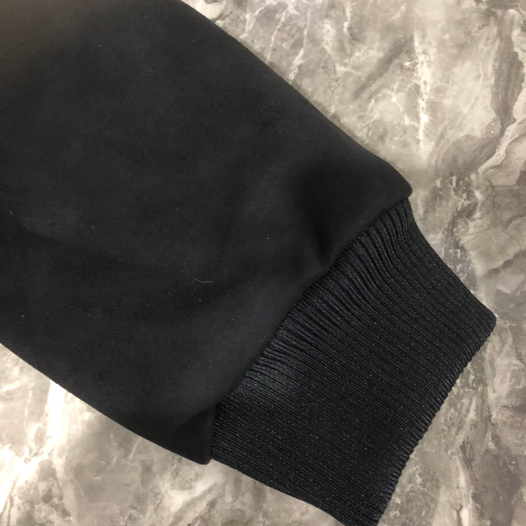 Dior long jacket sleeve cuff close-up with ribbed knit cuff on dark fabric