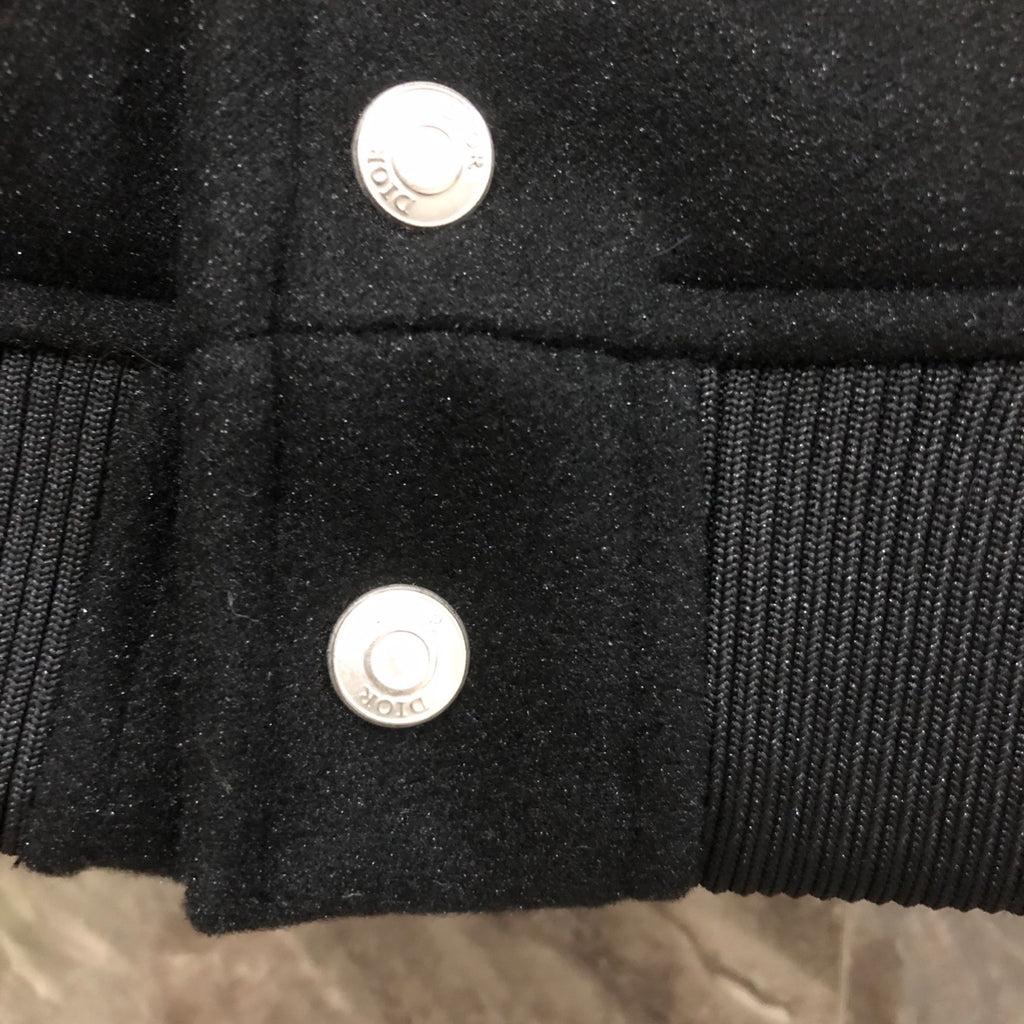 Dior long jacket front close-up showing two silver snap buttons on dark fabric