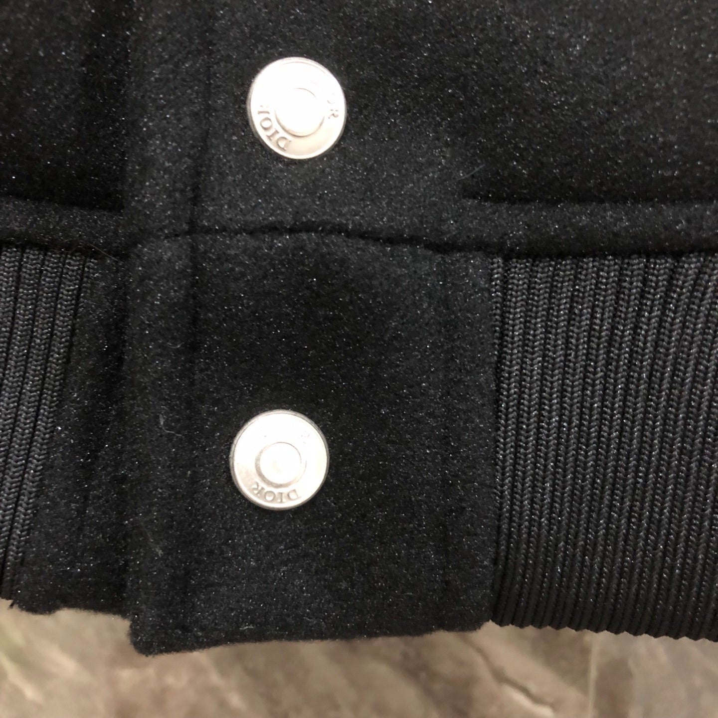 Dior long jacket front close-up showing two silver snap buttons on dark fabric