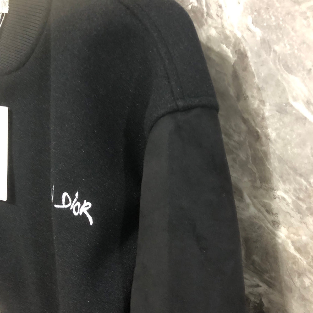 Dior long jacket side close-up with embroidered logo on dark fabric
