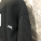 Dior long jacket side close-up with embroidered logo on dark fabric