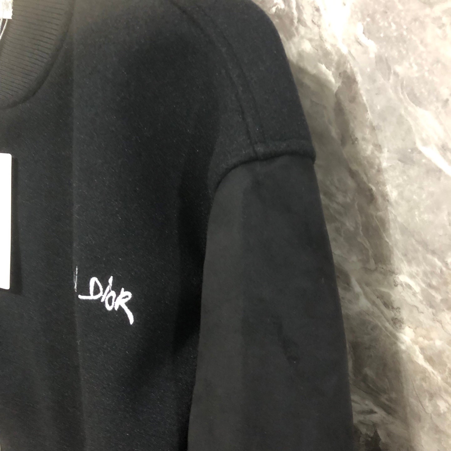 Dior long jacket side close-up with embroidered logo on dark fabric