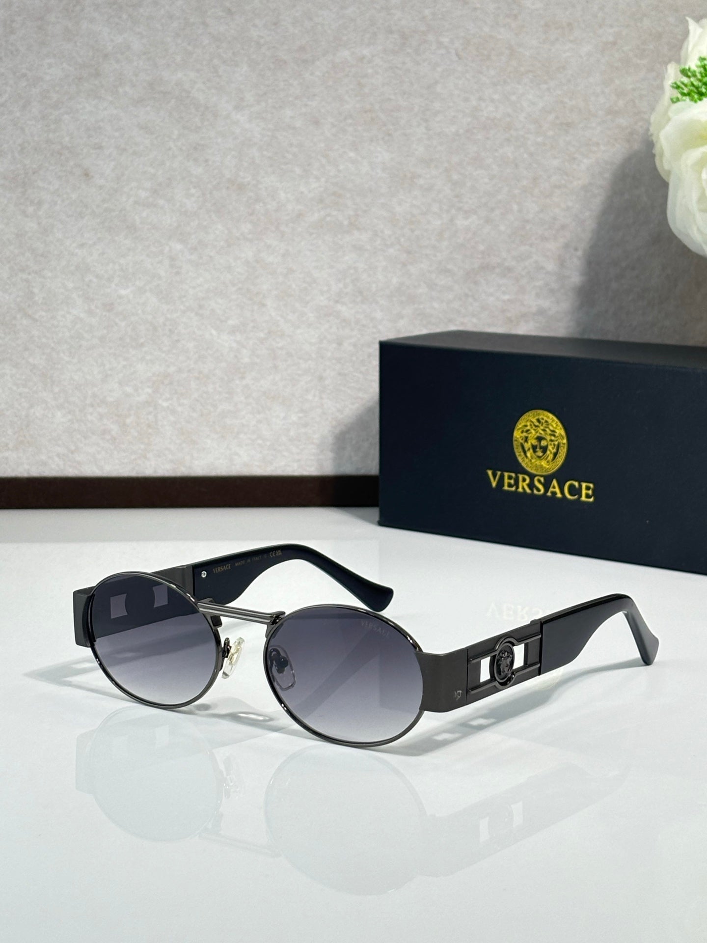 Round sunglasses with black frames and gold detailing; dark tinted lenses.