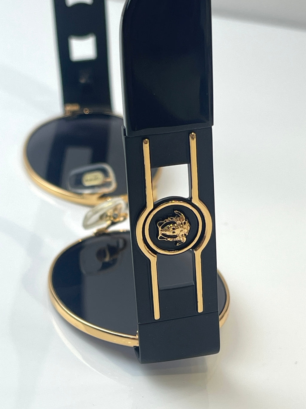 Round sunglasses with navy frames and gold trim, shown near an open case.