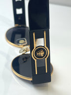 Round sunglasses with navy frames and gold trim, shown near an open case.