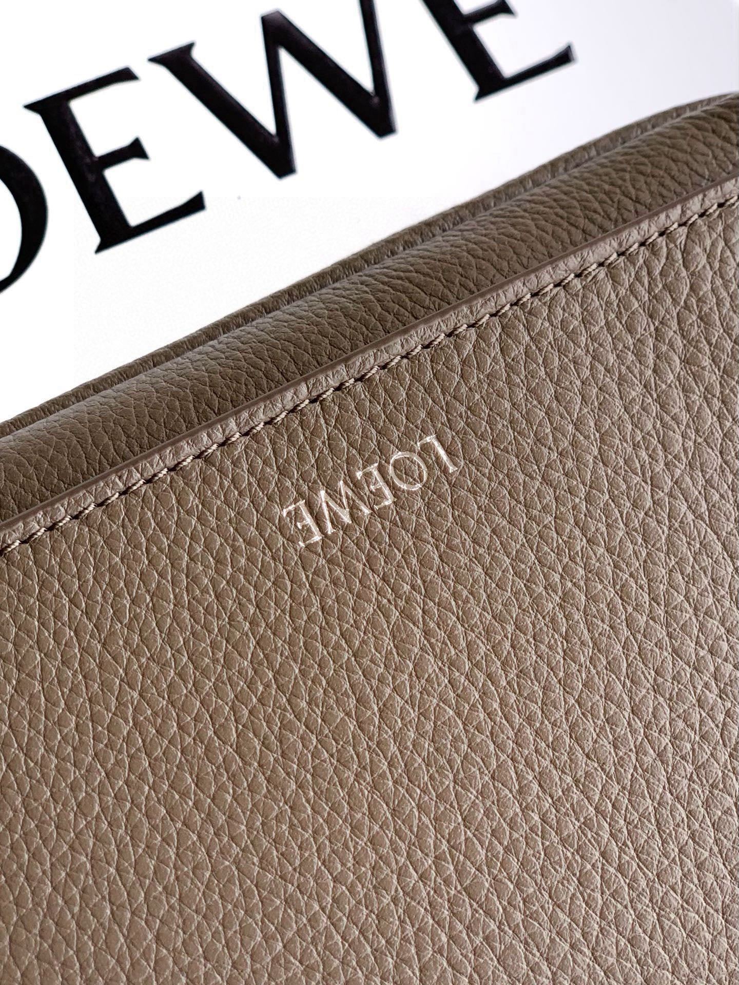 Taupe leather bag panel with embossed logo and fine-grain texture