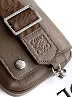 Taupe leather strap detail with metal buckle and embossed emblem