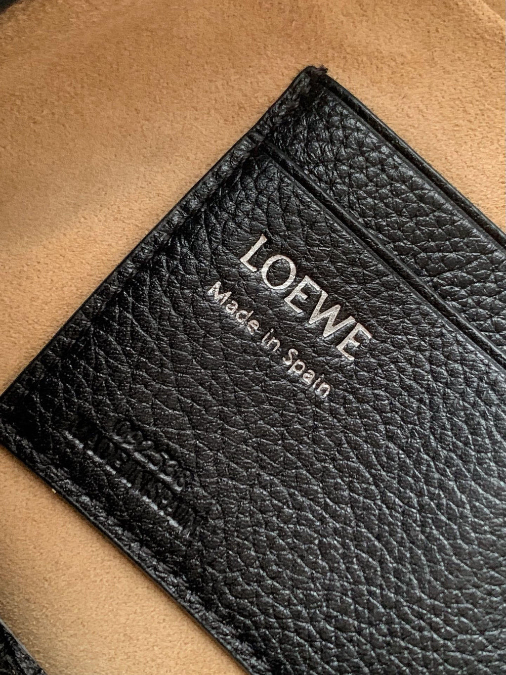 Men's leather detail with LOEWE text and Made in Spain stamp on black grainy surface