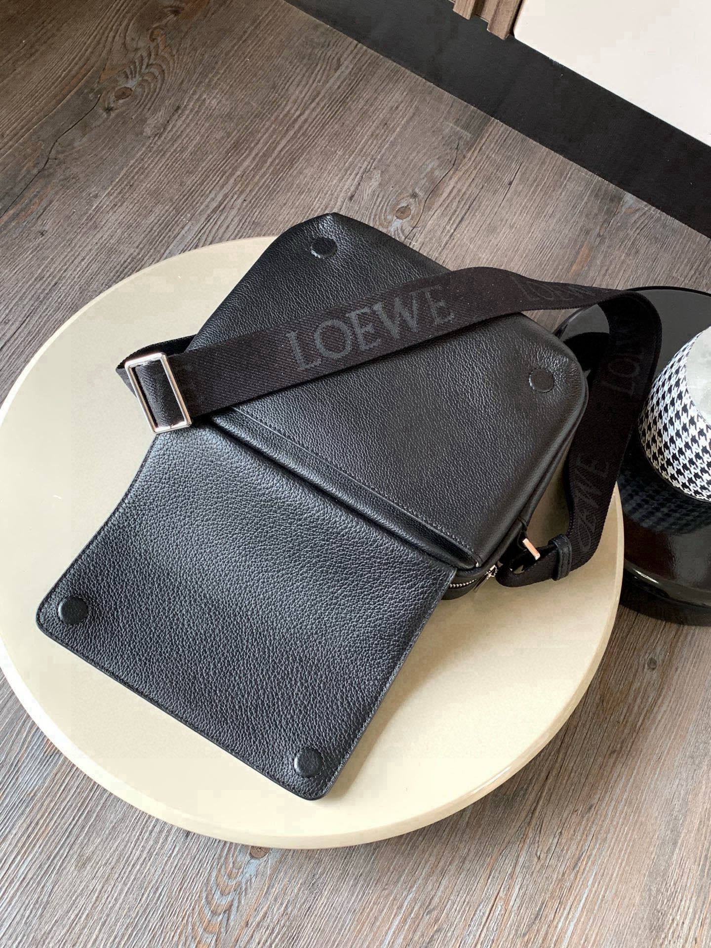 Pebbled leather crossbody bag with snap buttons, strap, and metal buckle