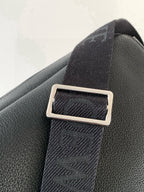 Pebbled leather bag with rectangular metal strap holder and woven webbing