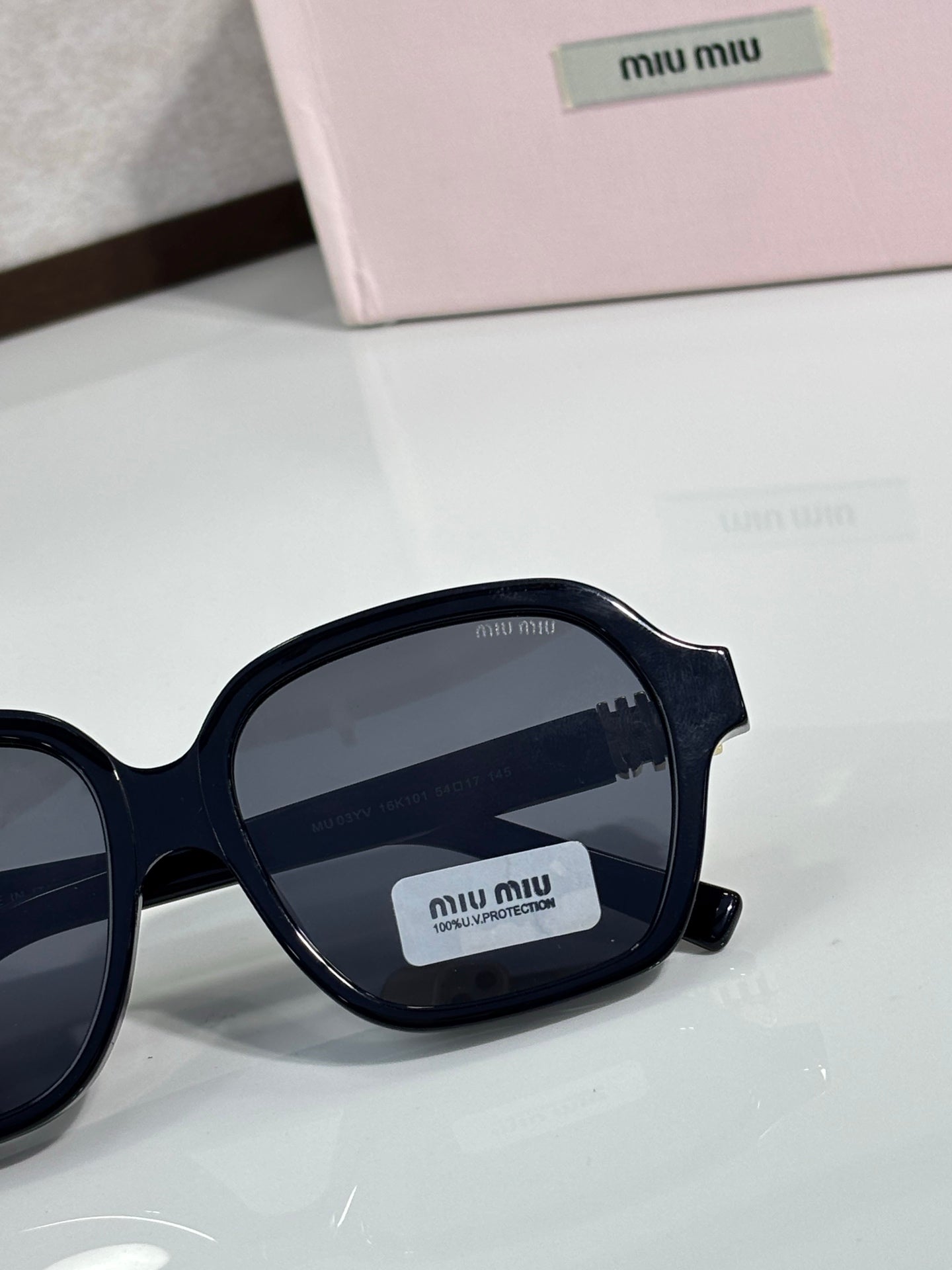 MiuMiu navy round-square eyeglass frame close-up with dark lens and gold logo