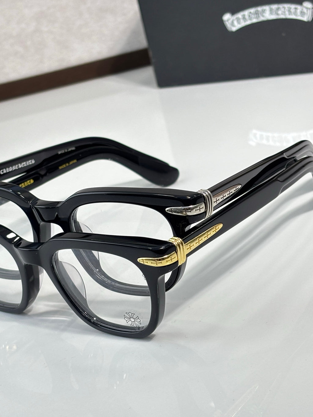 Black full-rim eyeglasses with gold temple detailing and rectangular lenses