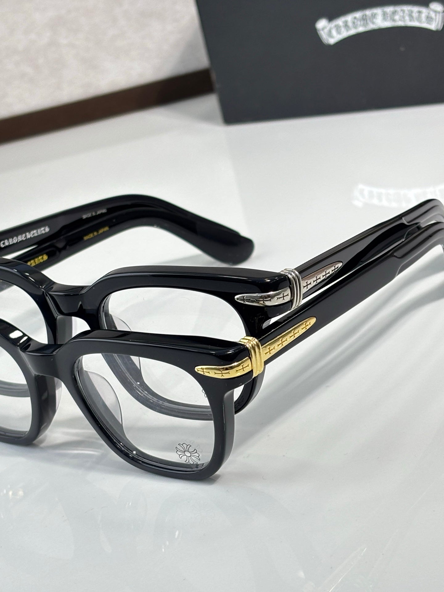 Black full-rim eyeglasses with gold temple detailing and rectangular lenses
