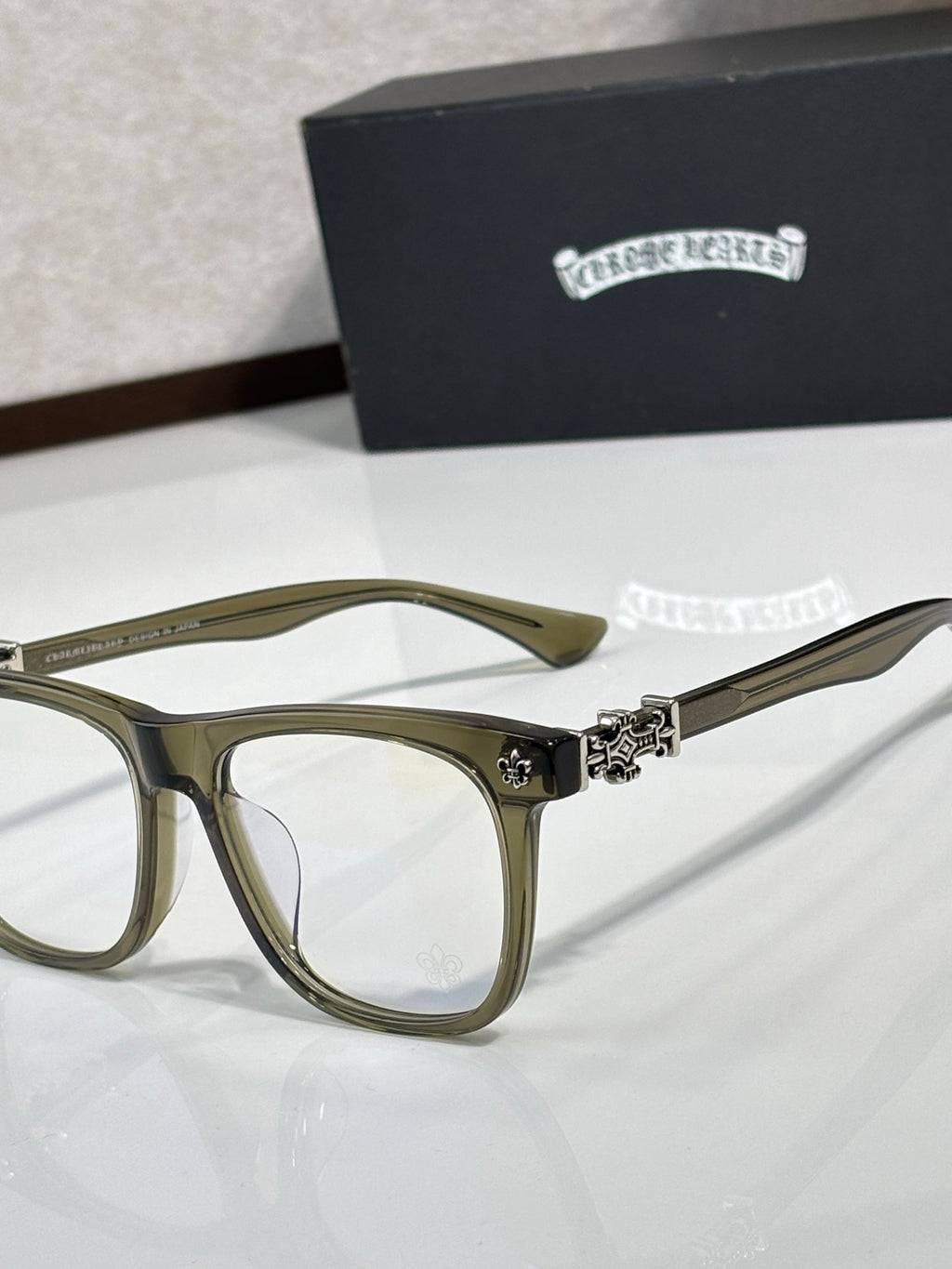 Chrome glasses with olive rectangular frames and clear lenses, decorative hinge at temple