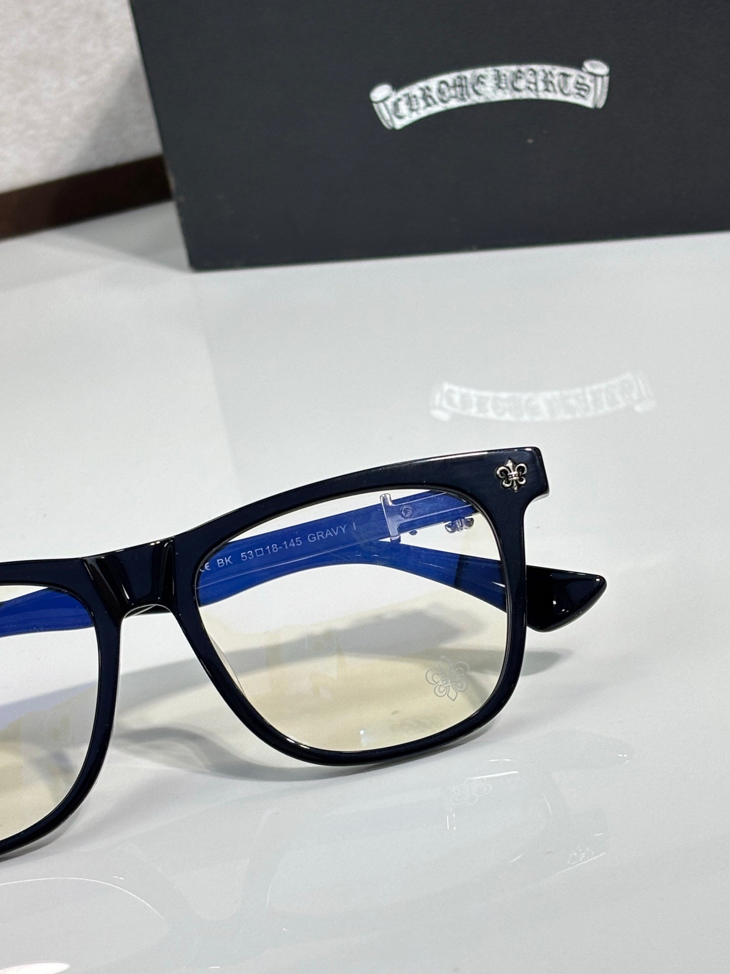 Chrome glasses with dark navy frame and side temple decoration, clear lens view