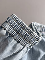 Louis Vuitton light blue denim pants cuff close-up, elastic gathered waistband