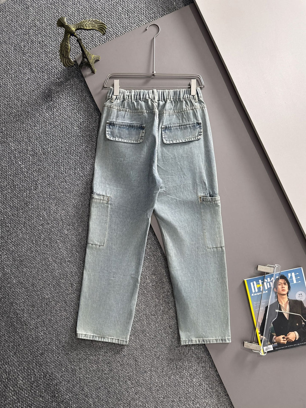 Light blue denim pants with flap pockets, stitched seams, and front button closure