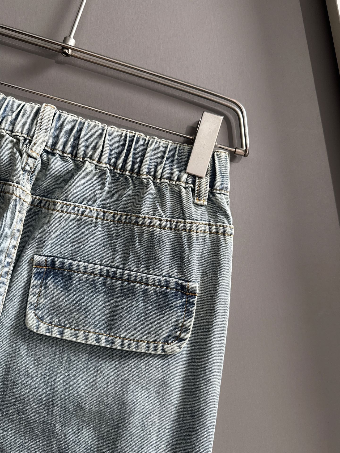 Light blue denim pants close-up of elastic waistband and front flap pocket