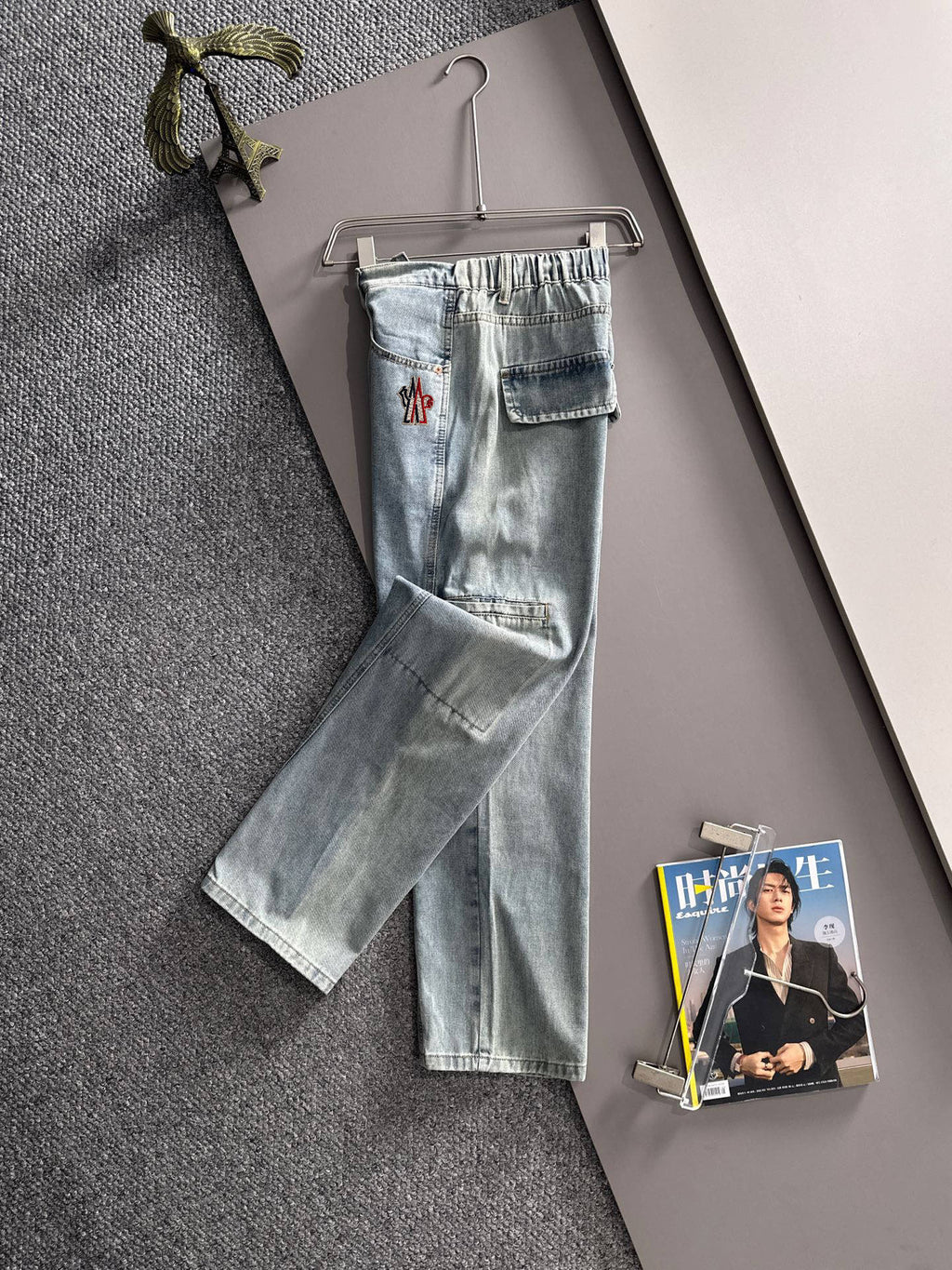Light blue denim pants hanging on a hanger with cuffed hem and flap pockets