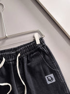Dior dark denim pants close-up of elastic waistband and drawstring, logo patch
