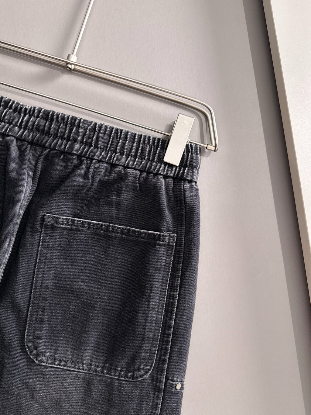 Dior dark denim pants close-up of elastic waistband and front pocket with stitching