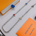 Silver charm necklace with red and blue charms and green flower pendant