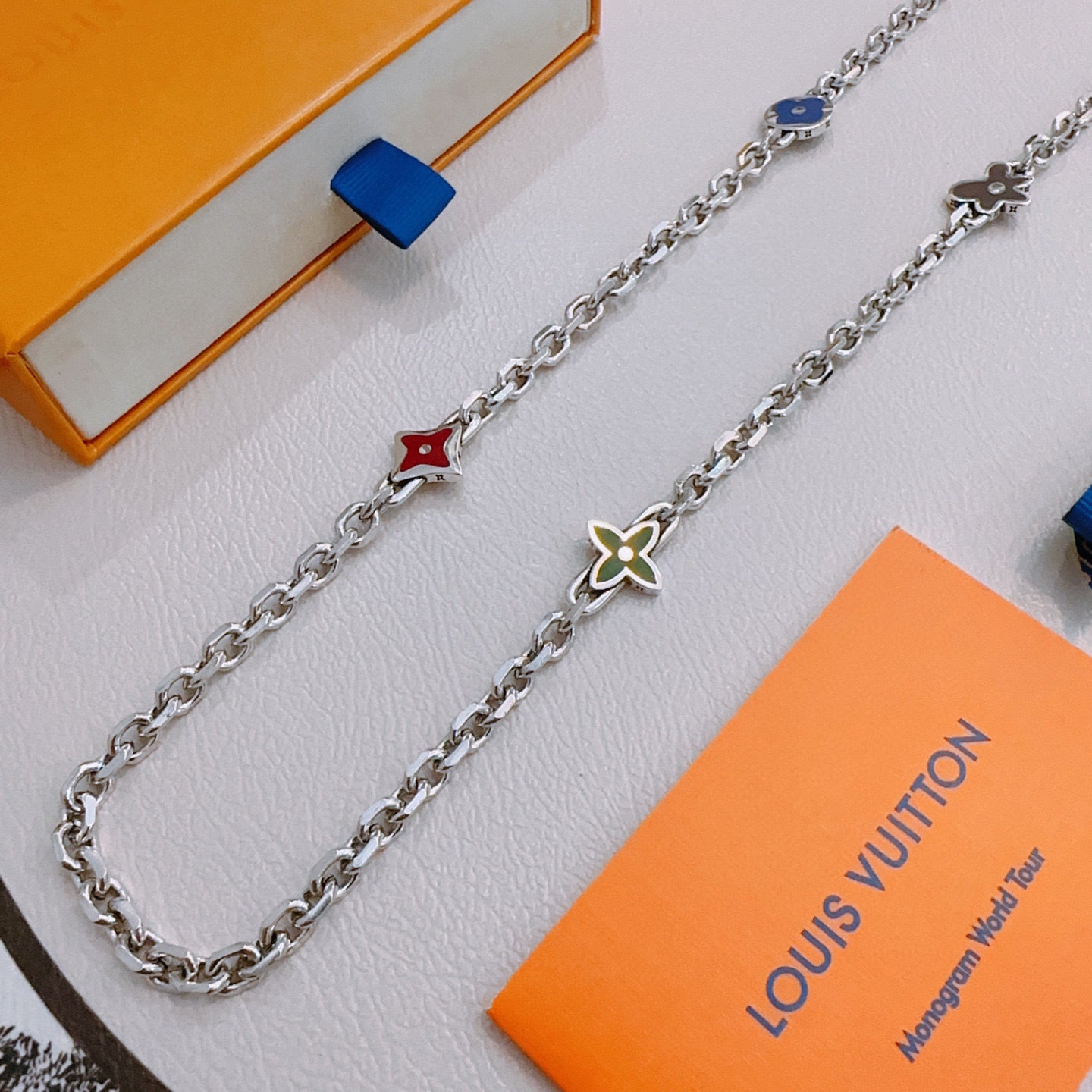 Silver charm necklace with red and blue charms and green flower pendant