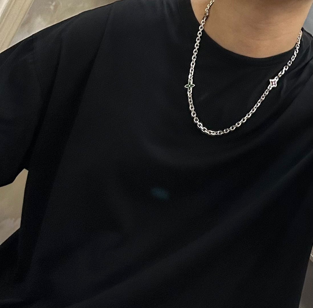 Silver chain necklace with small cross pendant on a black crewneck shirt