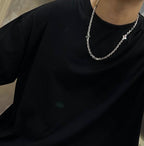 Silver chain necklace on a black crewneck shirt
