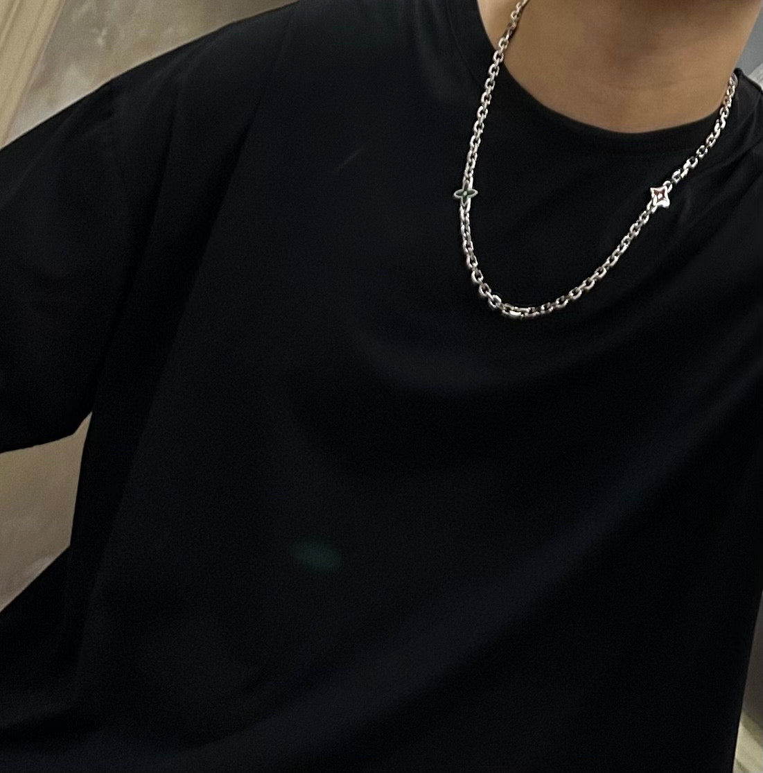Silver chain necklace on a black crewneck shirt