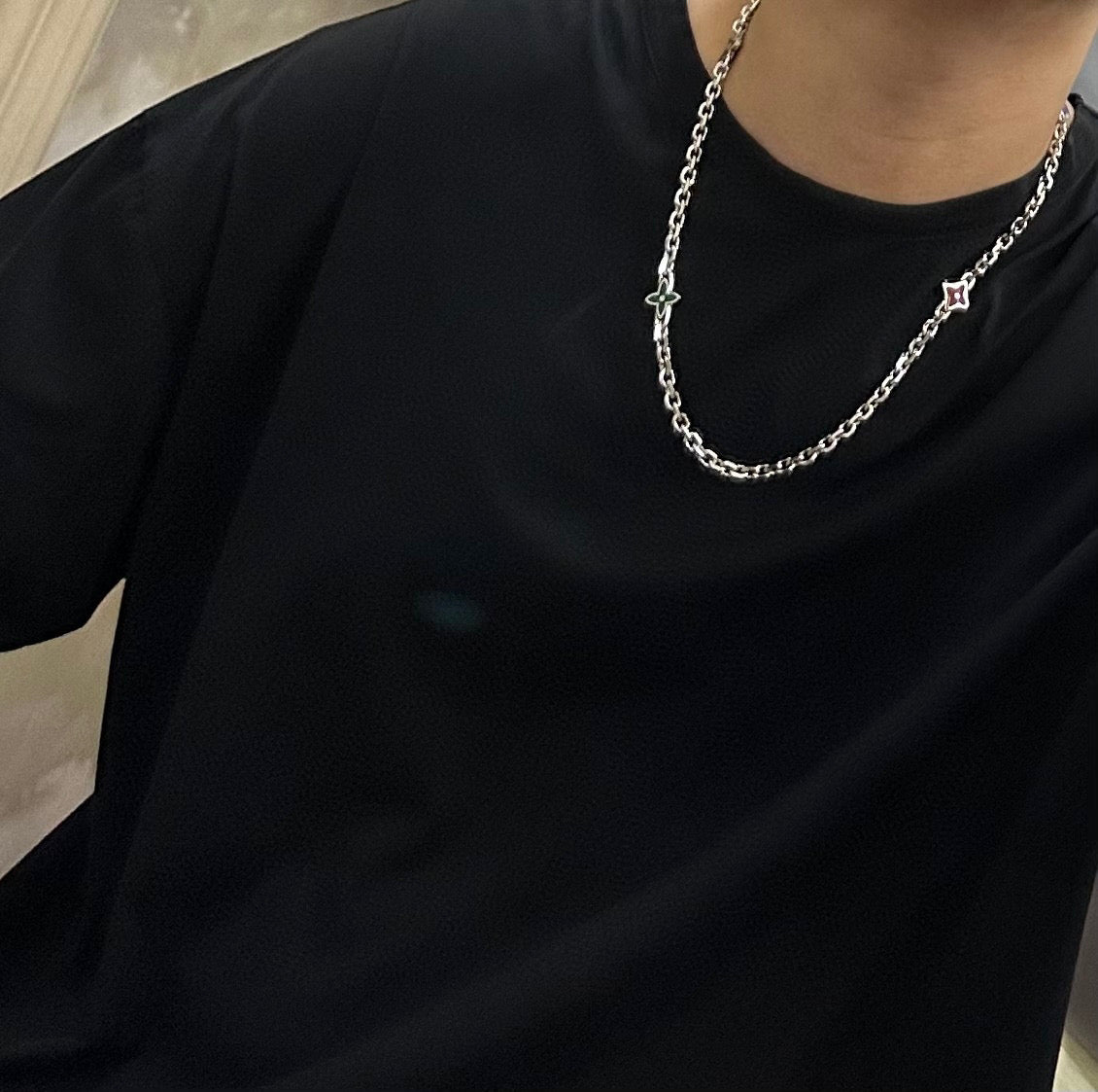 Silver chain necklace with small cross pendant on a black crewneck shirt