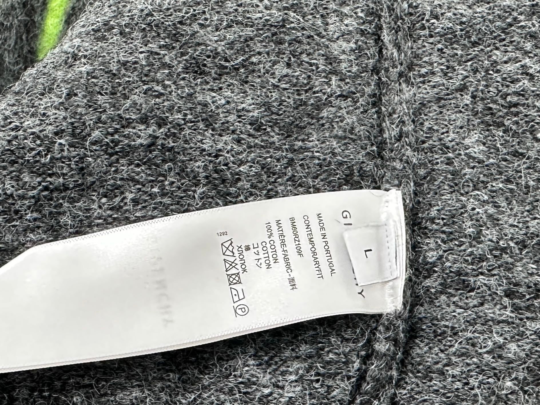 Fuzzy dark gray sweater fabric with white size label and care instructions