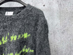Dark gray fuzzy knit sweater with neon green graphic lettering, close view