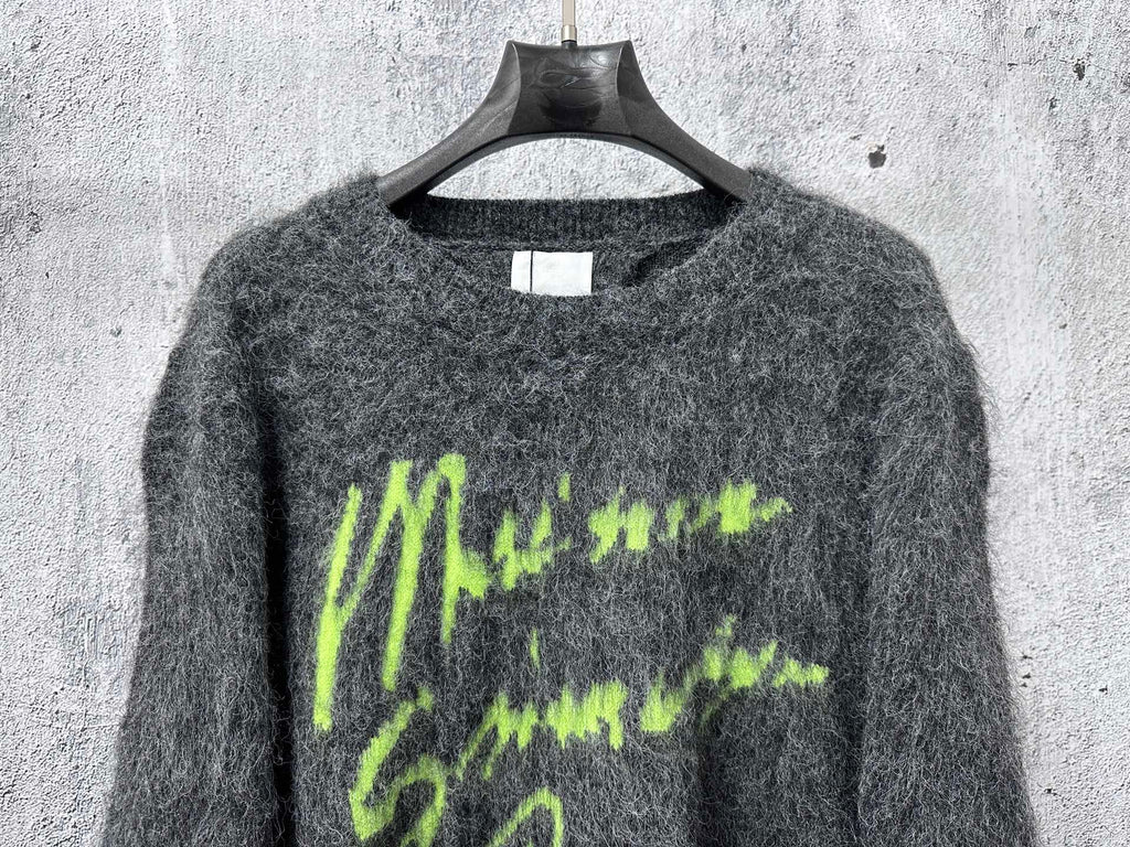 Dark gray fuzzy knit sweater with neon green graphic lettering on chest