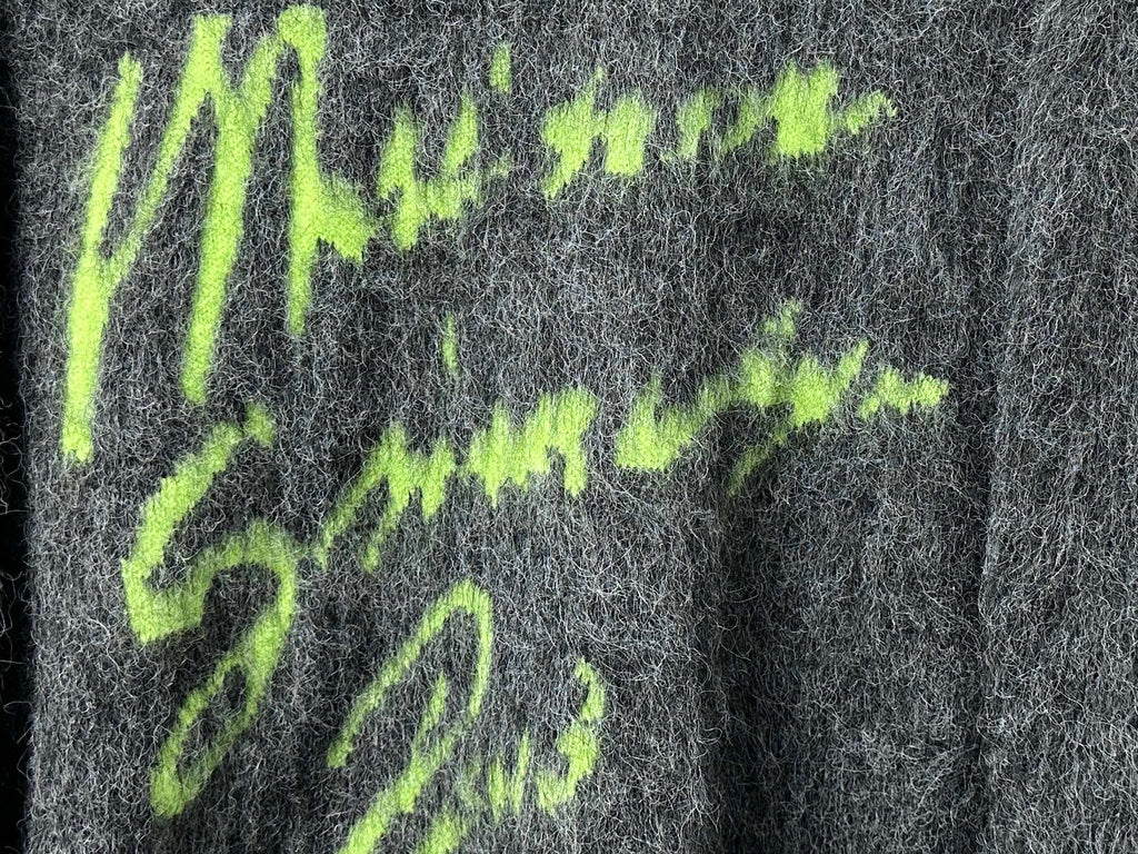 Dark gray fuzzy knit sweater close-up of neon green graphic lettering