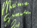 Dark gray fuzzy knit sweater close-up of neon green graphic lettering