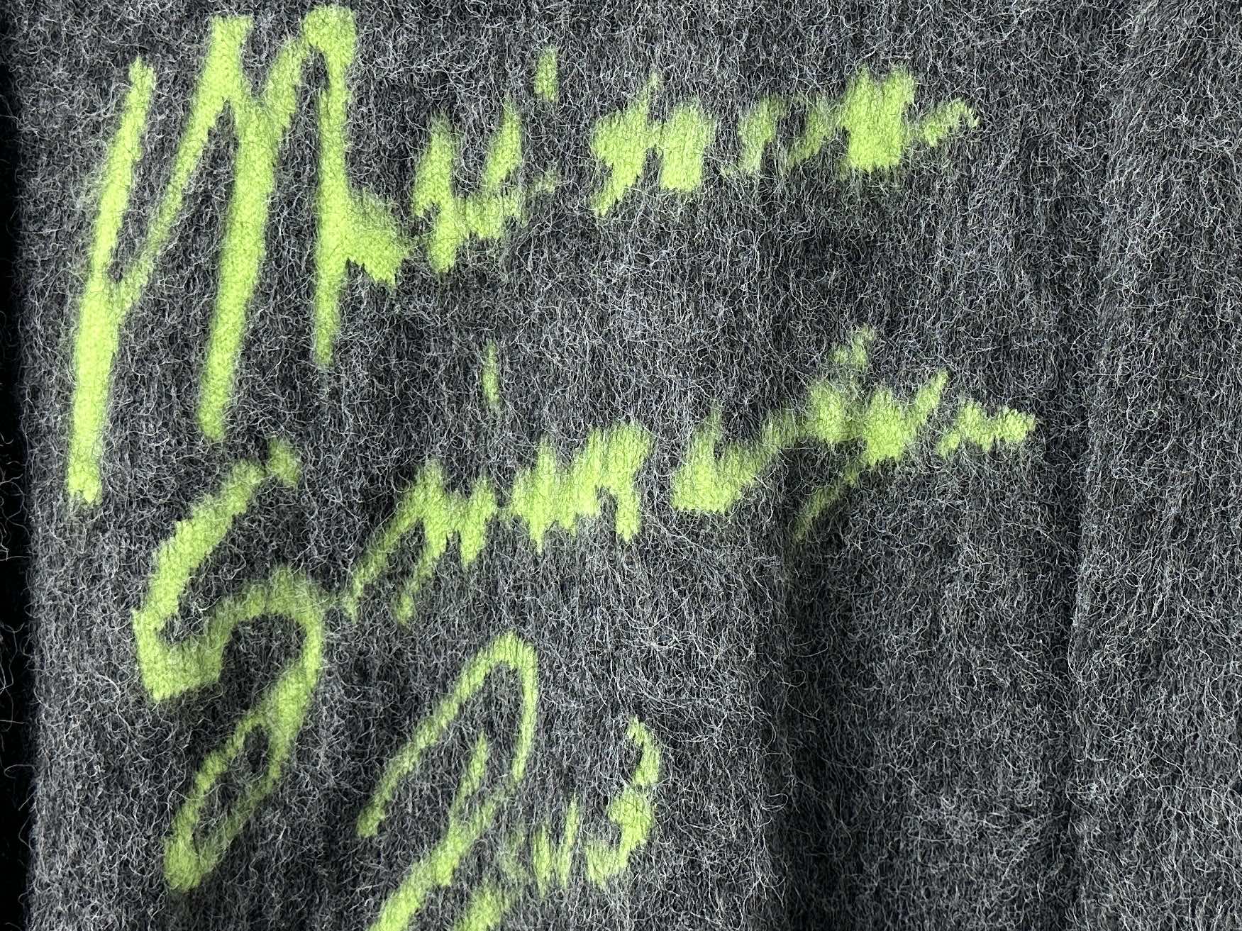 Dark gray fuzzy knit sweater close-up of neon green graphic lettering
