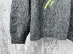 Dark gray fuzzy knit sweater with neon green mark at side and ribbed hem