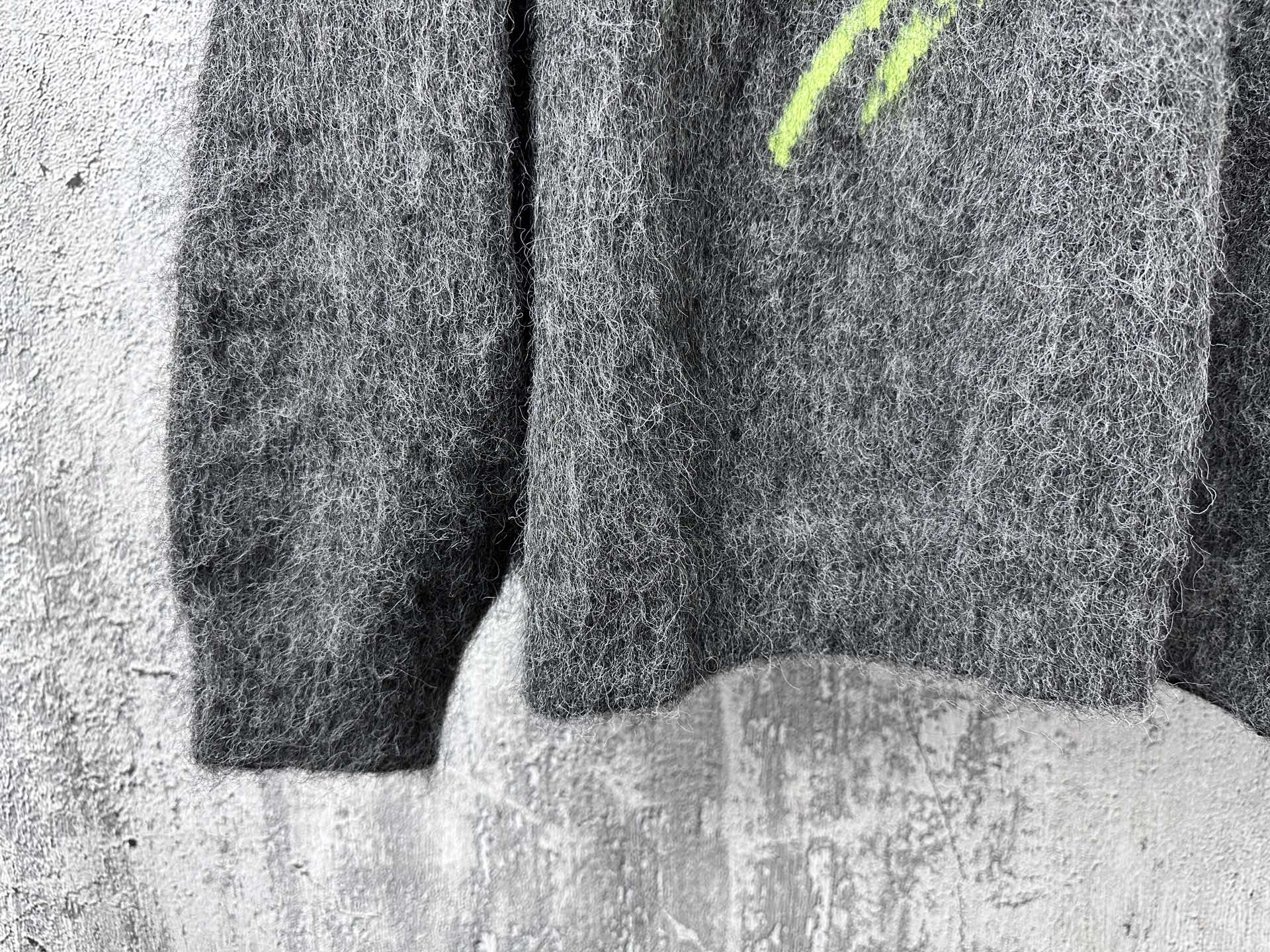 Dark gray fuzzy knit sweater with neon green mark at side and ribbed hem
