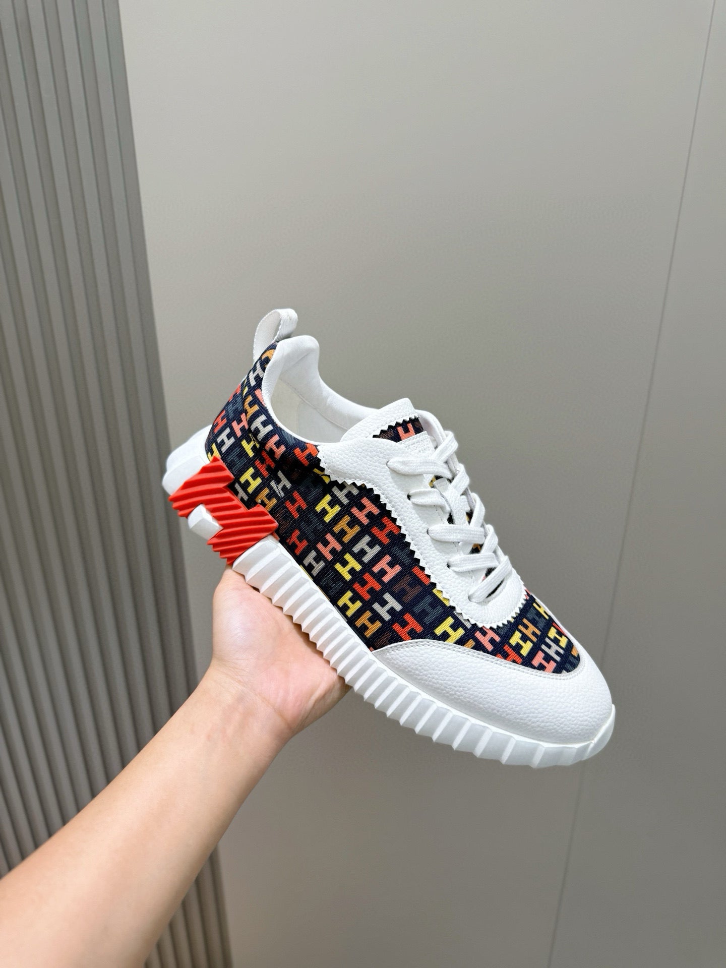 Hermes unisex sneaker close-up, patterned upper with white midsole and side stripe