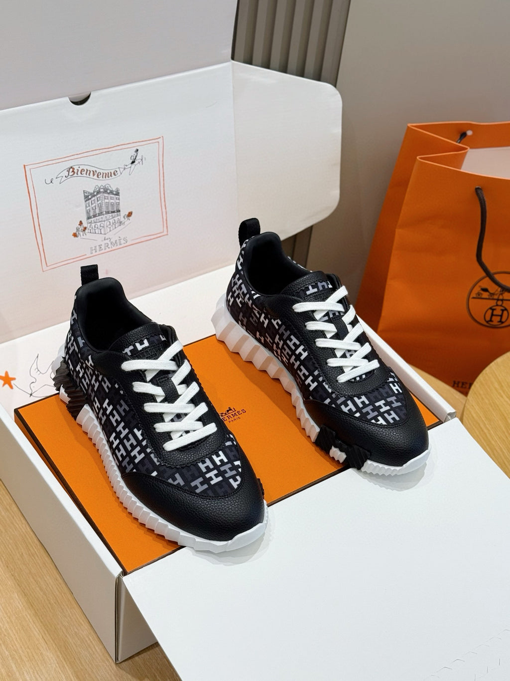 Black low-top sneakers with white laces and repeating H-style logo pattern