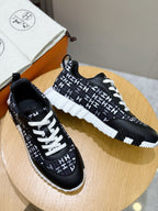 Two black low-top sneakers with white laces and repeating H-style logo pattern