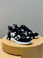 Unisex cow-print sneakers on display, black top with white pattern, white sole.