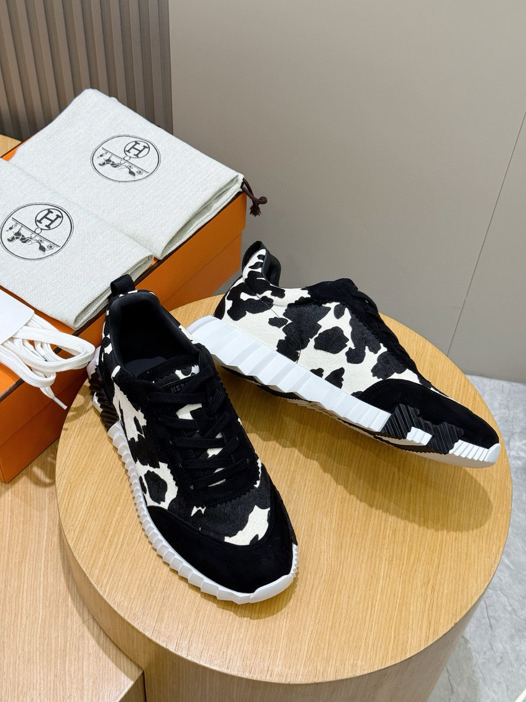 Unisex cow-print sneakers pair, black-and-white pattern, lace-up design, white sole.