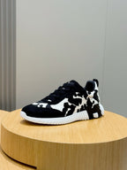 Cow-print unisex sneakers with black laces, low profile, white ridged sole.