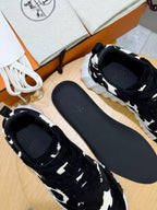 Pair of unisex cow-print sneakers, black uppers with white spots, black inner lining.