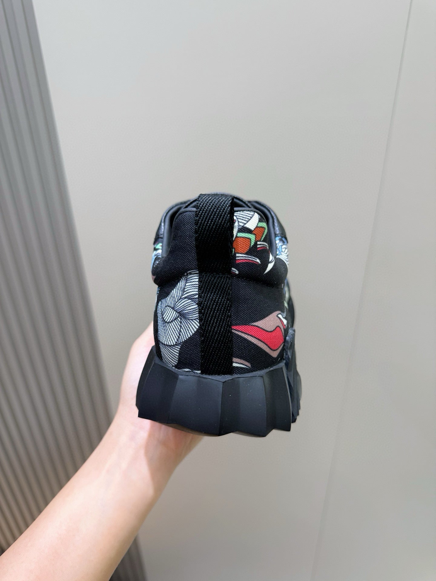 Black unisex sneaker heel with multicolor textile lining and lace-up strap.